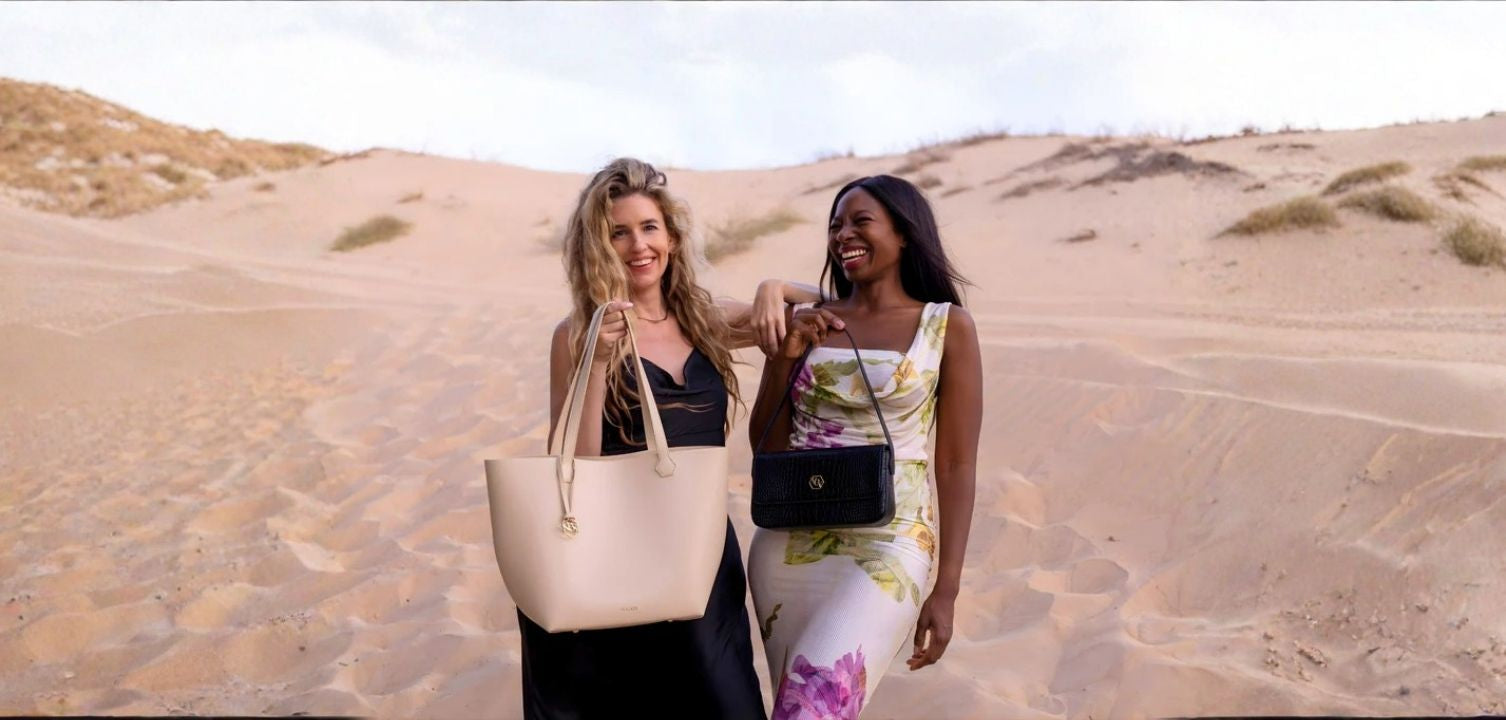 Two women holding handbags in a desert setting